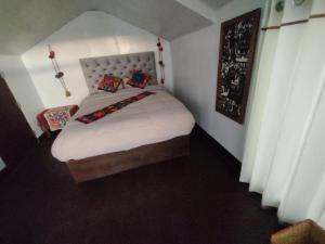 a small bedroom with a bed with white sheets and pillows at TITICACA WORLDWIDE LODGE in Puno