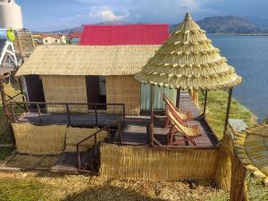 eine Hütte mit einer Terrasse mit Stühlen und einem Sonnenschirm in der Unterkunft TITICACA WORLDWIDE LODGE in Puno