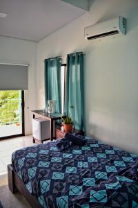 a bedroom with a bed and a dresser and a window at Ocean's Breeze Apartment and Rooms in Puerto Viejo