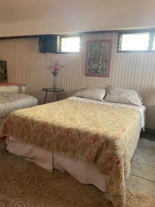 a bedroom with two beds and a table and two windows at Habitación privada Barrio Uno in Ezeiza