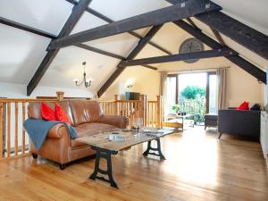 sala de estar con sofá de cuero y mesa en Uk45543-the Threshing Barn, en Sticklepath