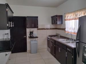 a small kitchen with black cabinets and a sink at STARFISH Maeva Residencial in Puerto Peñasco