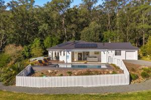 een huis met een zwembad en een wit hek bij Birdsong, Kangaroo Valley in Barrengarry