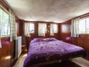 um quarto com uma cama roxa num quarto com janelas em Cozy Boat in Merkem near Lake em Drie Grachten