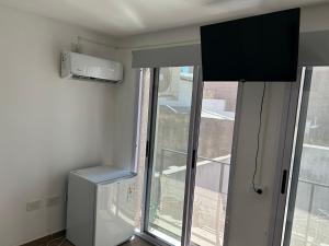 um quarto com uma janela, um frigorífico e uma televisão em Cálido MonoAmbiente SinCochera em Rosário
