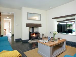 a living room with a fireplace and a blue couch at Uk45541-old Stable Cottage in Sticklepath
