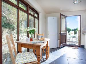 uma cozinha com uma mesa de madeira e um frigorífico em Uk45541-old Stable Cottage em Sticklepath