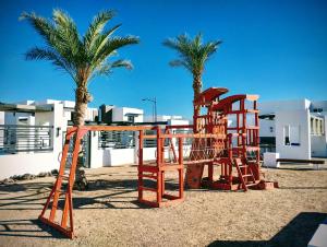 a playground with a slide and two palm trees at STARFISH Maeva Residencial in Puerto Peñasco