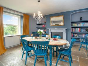 a dining room with blue chairs and a table and a fireplace at Uk45542-the Farm House in Sticklepath