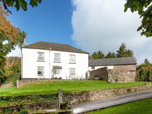 a white house with a stone wall and green yard at Uk45542-the Farm House in Sticklepath