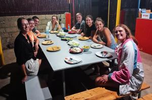 un grupo de personas sentadas alrededor de una mesa comiendo comida en Footprints Hostel en Corón