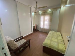 een kamer met een bed, een stoel en een raam bij Apartment near airport in Caïro