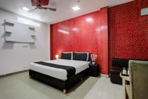 um quarto com uma cama e uma parede vermelha em Thirty Inns em Noida
