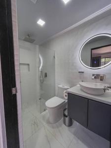 een badkamer met een wastafel, een toilet en een spiegel bij Fortu House in Carrillo