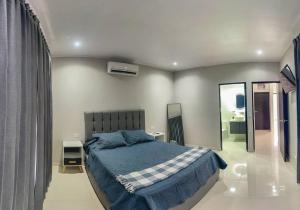 1 dormitorio con 1 cama grande con manta azul en Fortu House, en Carrillo