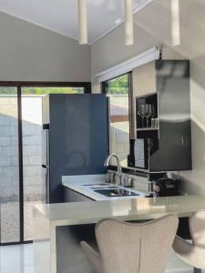 a kitchen with a sink and a counter with chairs at Fortu House in Carrillo