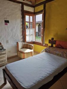 um quarto com uma cama, uma cadeira e uma janela em Aconchego em Ilhabela em Ilhabela