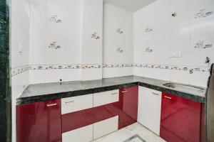 una cocina con armarios rojos y blancos y fregadero en OYO Flagship Galaxy Grand B&B, en Panvel