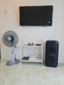 a room with a fan and a television on a wall at DeiHouse in Samal
