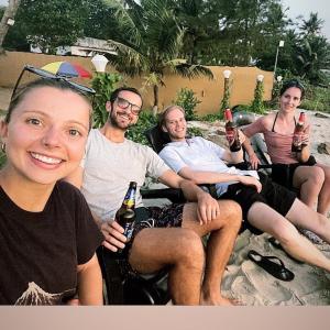 Tripsea Beach Villa في أليبي: مجموعة من الناس يجلسون على الشاطئ مع البيرة