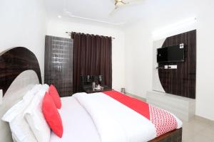 a bedroom with a white bed with red pillows at Hotel Kamal Palace in Chandīgarh