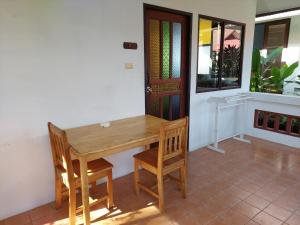 drewniany stół i dwa krzesła przed drzwiami w obiekcie Fullmoon House Samui w mieście Lamai