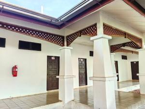 a white building with brown doors and pillars at Deluxe Room in Pendang