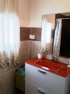 een badkamer met een rode wastafel en een spiegel bij casa familiar in San Fernando