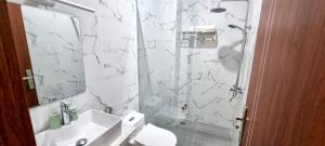 a white bathroom with a sink and a shower at Sunn Hotel in Vung Tau