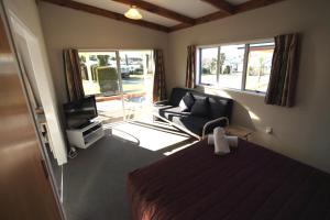 a bedroom with a bed and a couch and a television at Timaru TOP 10 Holiday Park in Timaru