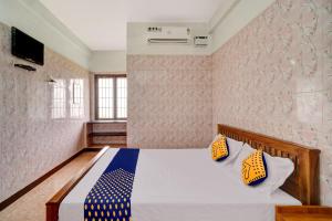um quarto com uma cama com almofadas azuis e amarelas em OYO Flagship Sri Balaji Lodge Non Ac em Pollāchi