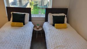 two beds sitting next to a window in a room at B43 Cosy Home - Contractor-Family Stays Near Bhm City-Off Road Parking Free Wi-fi in Holly Lane