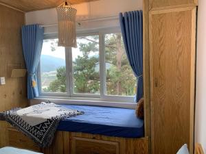 a small room with a window with a blue curtain at Belle House Đà Lạt in Da Lat