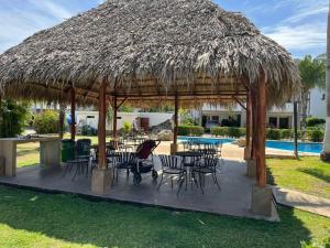 une femme assise sur une chaise sous un parapluie de paille dans l'établissement Full condo in Tamarindo, CR, à Tamarindo