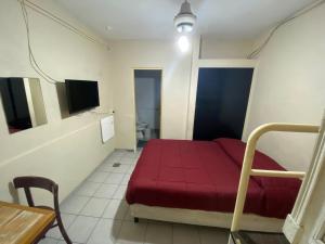 Habitación pequeña con cama roja y mesa. en Mitre Suites en Buenos Aires