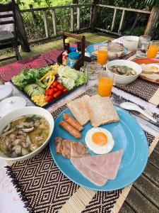 a table with a blue plate of food with eggs and vegetables at The Maewin Coffee & Cottage Economy Family Room in Ban Huai Rin