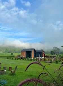 a house in the middle of a green field at The Maewin Coffee & Cottage Economy Family Room in Ban Huai Rin +2 photos