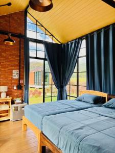 a bedroom with a bed and a large window at The Maewin Coffee & Cottage Economy Family Room in Ban Huai Rin