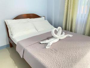 a bed with two white towels on it at Althea Apartelle in Moalboal
