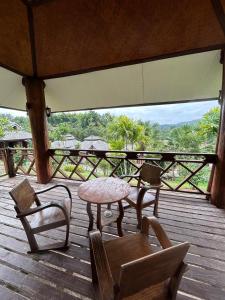 una mesa y sillas en una terraza de madera con vistas en Pai Love & Baan Chonphao Resort en Pai