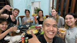 een groep mensen die rond een tafel zitten en eten bij Laoxao Homestay in Hội An