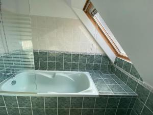 uma banheira na casa de banho com azulejos verdes em Pretty Holiday Home, Treffiagat em Tréffiagat