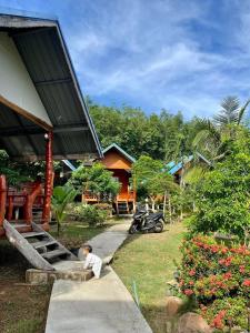 a little boy sitting on a sidewalk in front of a house at Happy Home Kohjum in Ko Jum