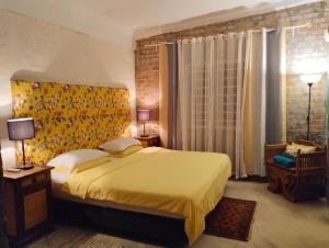 a bedroom with a large bed with a yellow blanket at Pondok Keladi Langkawi Guesthouse in Pantai Cenang