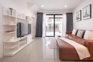 een woonkamer met een bank en een tv bij Chao Wilai Residence I Naiyang Beach I HKT Airport in Phuket