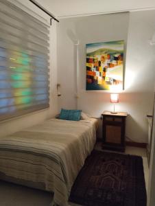 Pondok Keladi Langkawi Guesthouse في بانتايْ سينانج: غرفة نوم بسرير وطاولة مع مصباح