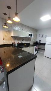 a kitchen with a black counter top and white appliances at Casa de Temporada no Paraíso de Arraial do Cabo in Arraial do Cabo