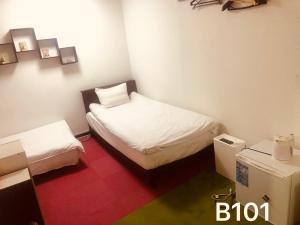 a small room with two beds and a refrigerator at 冠京ホテル in Tokyo