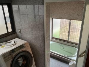 eine Waschküche mit einer Waschmaschine und einem Fenster in der Unterkunft ゆーみー. in Meinohama