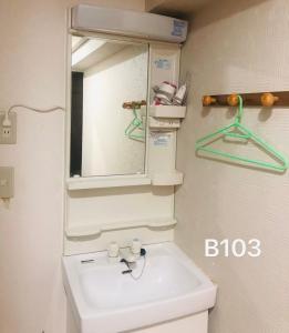 W łazience znajduje się biała umywalka i lustro. w obiekcie 冠京ホテル w Tokio